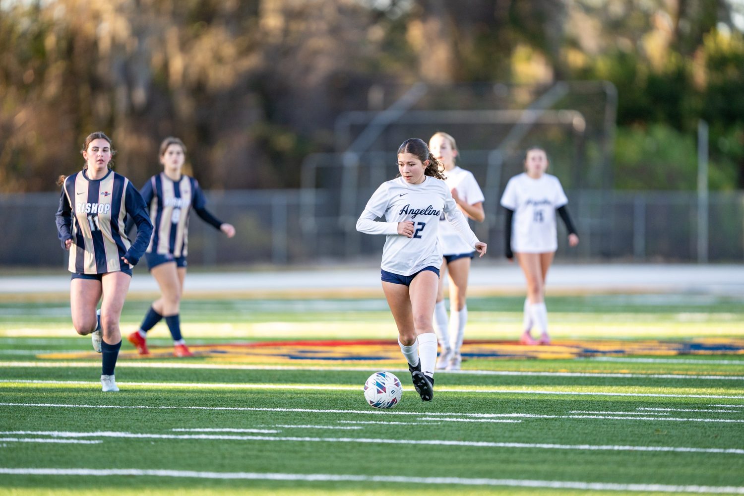 Eva Lowe, number 12, carrying the ball forward for Angeline Academy
